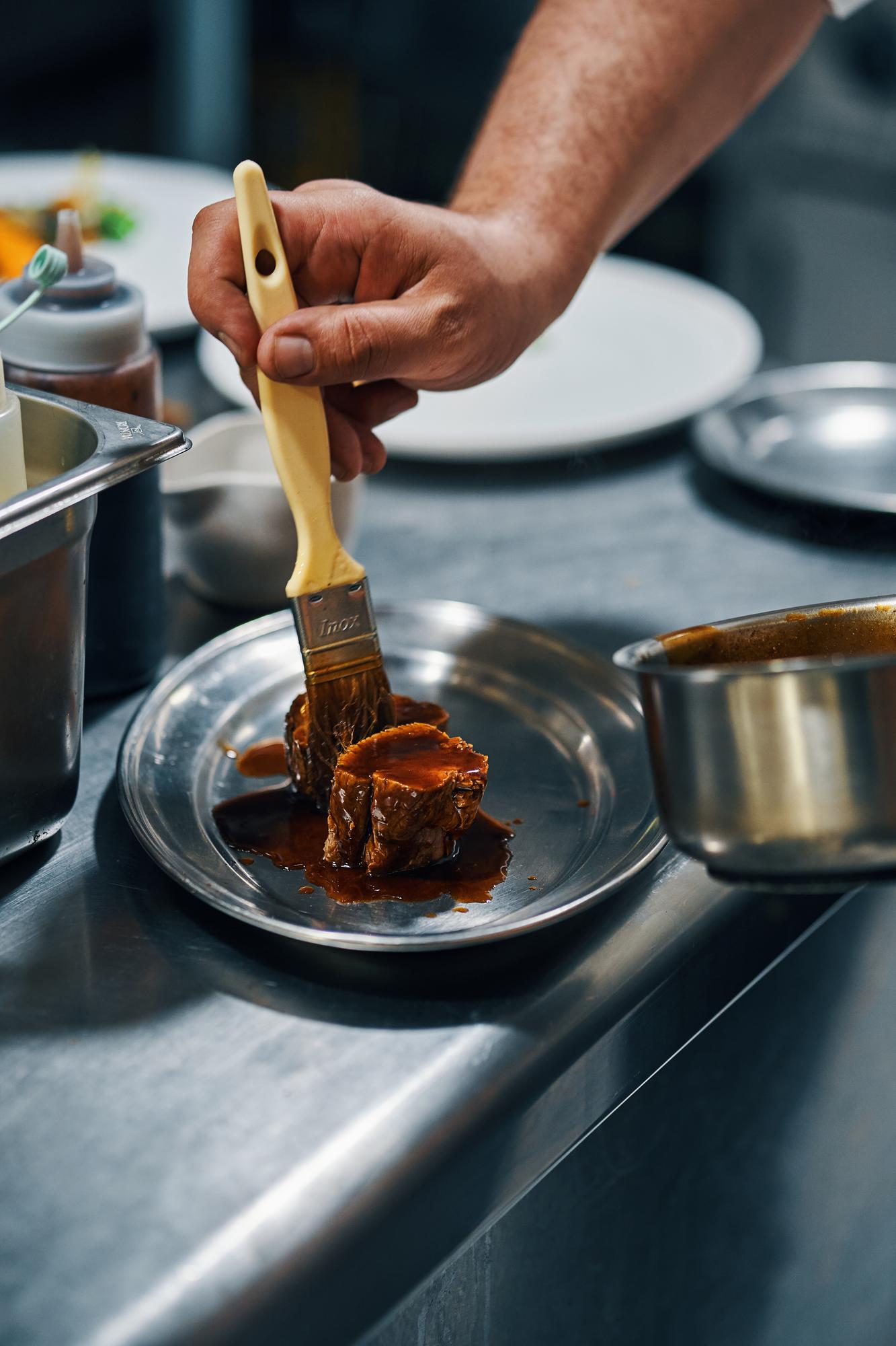 Close-up of a hand finishing sauce with brush