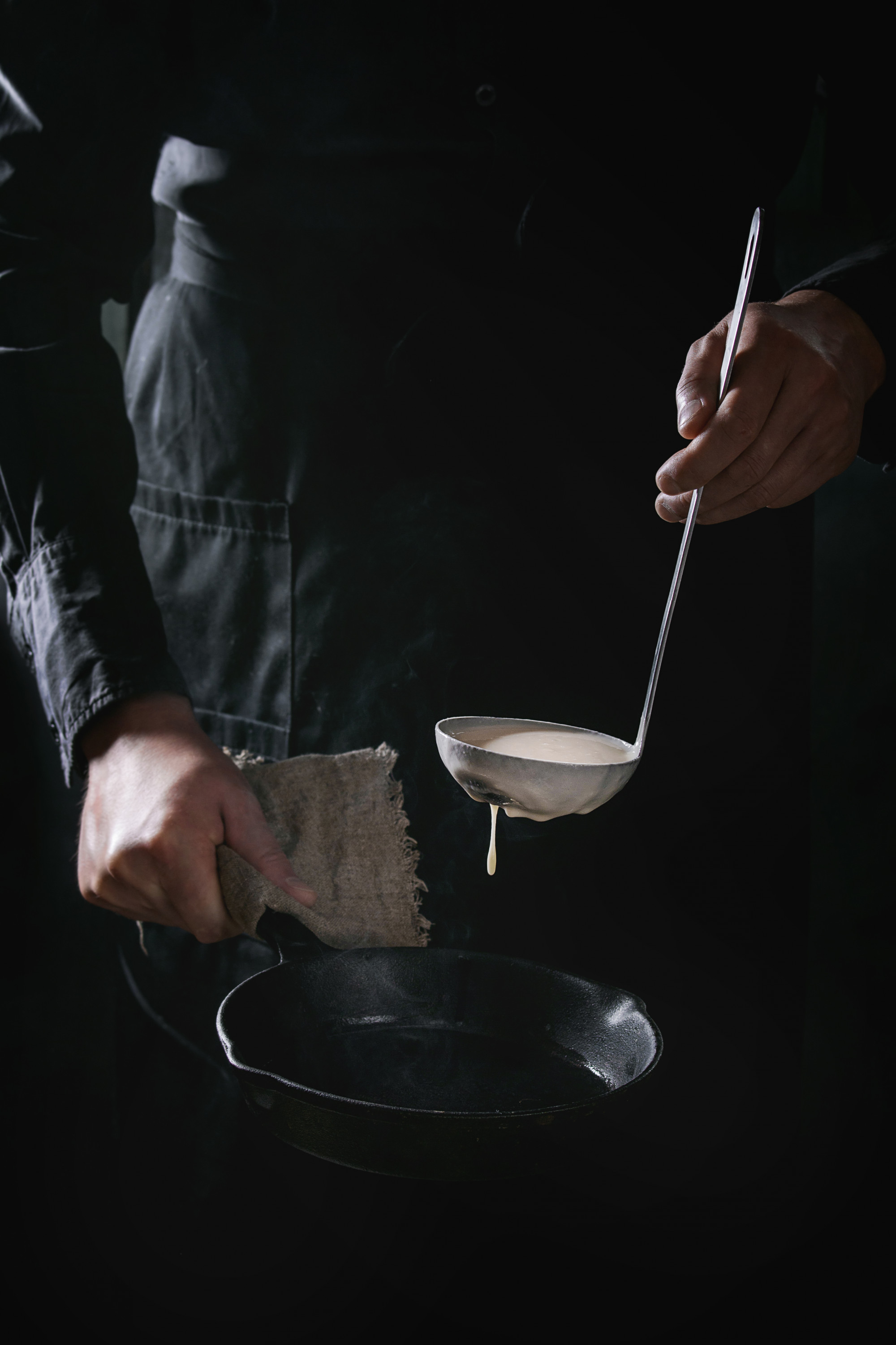 Chef arranging plated tasting menu on dark table